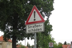 Wird auf Straßenschäden durch ein Schild hingewiesen, gilt es die Fahrweise anzupassen.